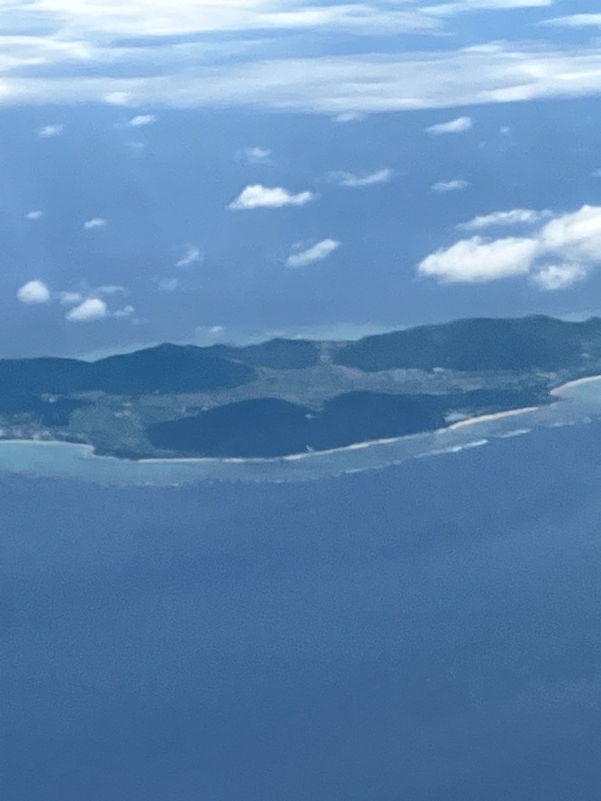 飛行機からの景色です。奄美あたりから高度が下がり、島が見え始めます。